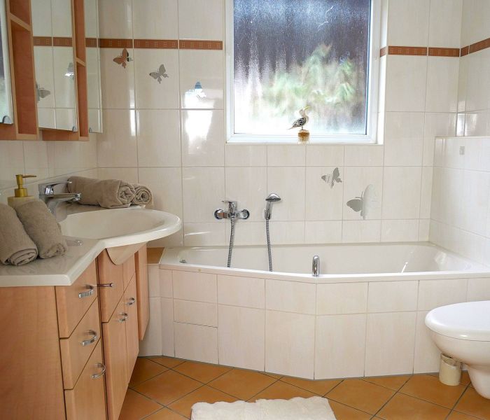 Helles Badezimmer mit Eckbadewanne und zwei Waschbecken.